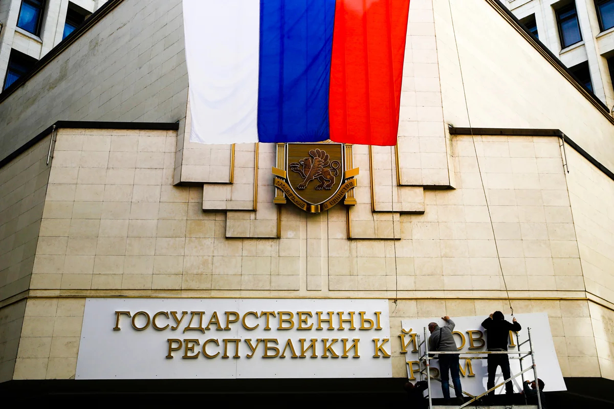 Рабочие устанавливают новую вывеску на здании госсовета в Симферополе, 19 марта 2014 года. Фото: Thomas Peter / Reuters / Scanpix / LETA