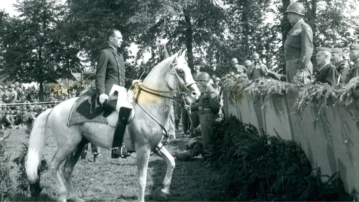 <span>Алоис Подхайски, австрийский офицер и наездник, руководивший Испанской школой верховой езды в Вене с 1939 по 1964 год, проводит демонстрационную езду на липпицианском жеребце перед генералом Джорджем Паттоном и военнослужащими армии США в знак благодарности за помощь американских войск при возобновлении работы школы. Зальцбург, Австрия, 28 августа 1945 года. Фото: akg-images / Scanpix / LETA</span>