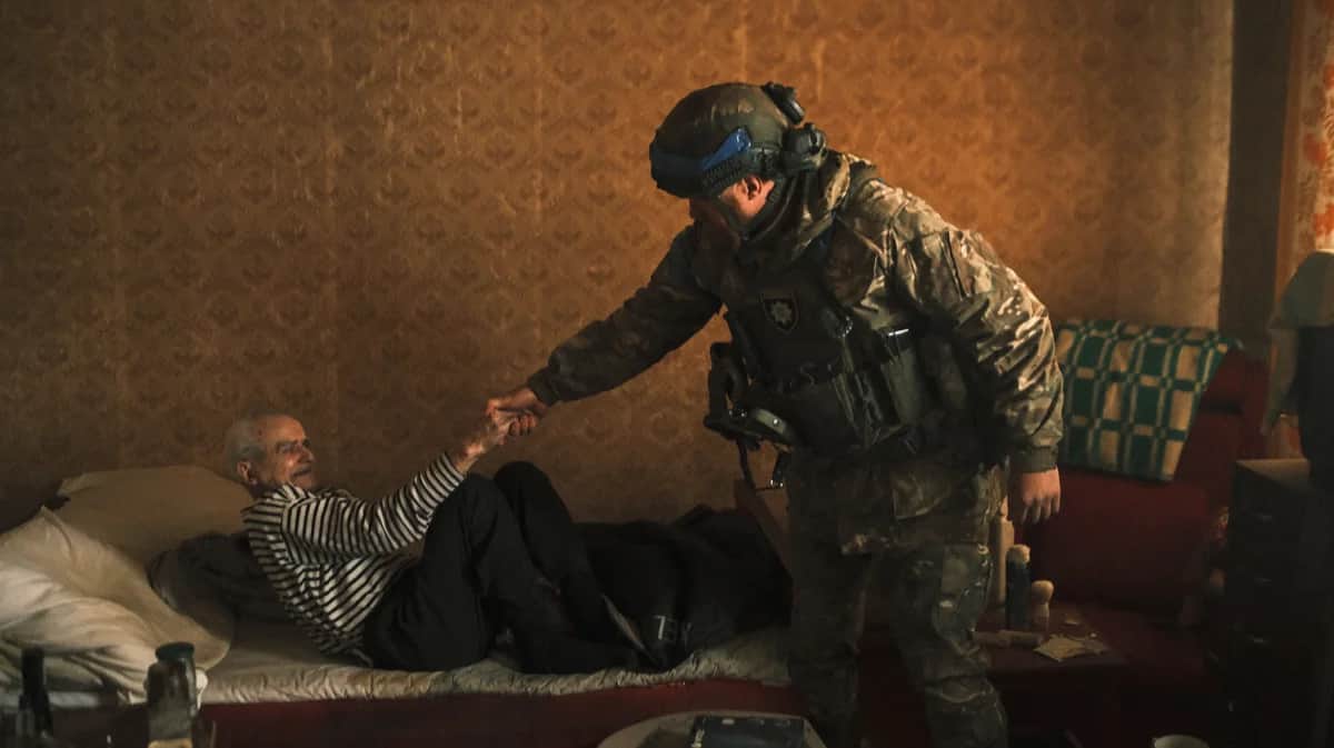 Украинский полицейский помогает пенсионеру эвакуироваться с территории, граничащей с Россией, в городе Волчанск Харьковской области, 13 мая 2024 года. Фото: Георгий Иванченко / EPA-EFE