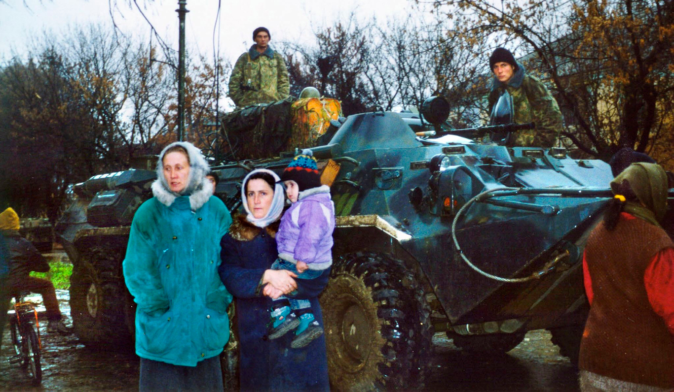 Чеченские женщины около бронетранспортера федеральных войск, патрулирующего улицы Гудермеса. Чечня. 13 ноября 1999 года. Фото: Эльмира Кожаева / EPA