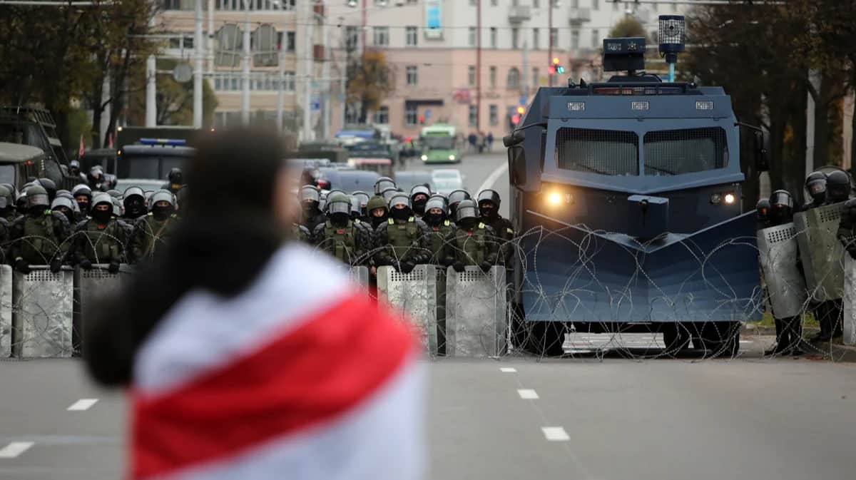 Протестующая стоит перед белорусскими полицейскими, перекрывающими дорогу во время антиправительственного митинга в Минске, Беларусь, 25 октября 2020 года. Фото: EPA