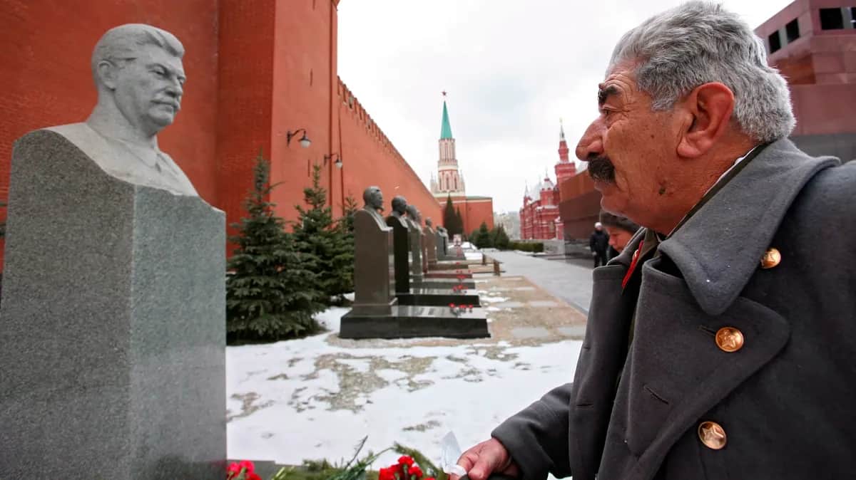 A Stalin lookalike comes face to face with a statue of Stalin marking the dictator’s grave under the Kremlin wall in Moscow. Photo: EPA/MAXIM SHIPENKOV